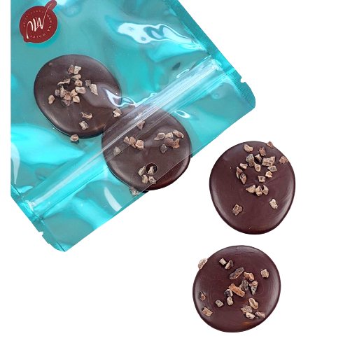 Cyan pouch with 4 dark chocolate disks topped with cocoa nibs coming out of it
