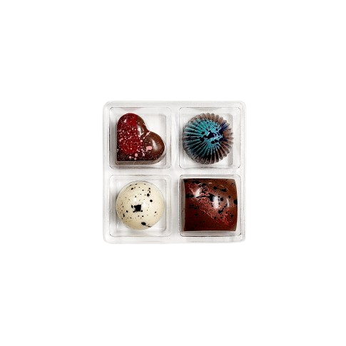 Four assorted chocolate bonbons in a clear plastic container on a white background