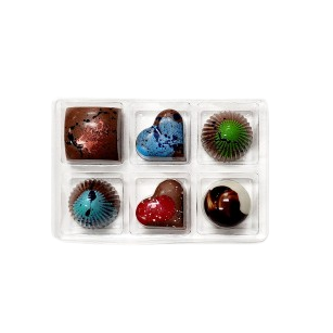Set of six colorful chocolate bonbons in a clear container on a white background